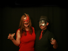 Masked woman in red dress, masked man in black suit with red tie